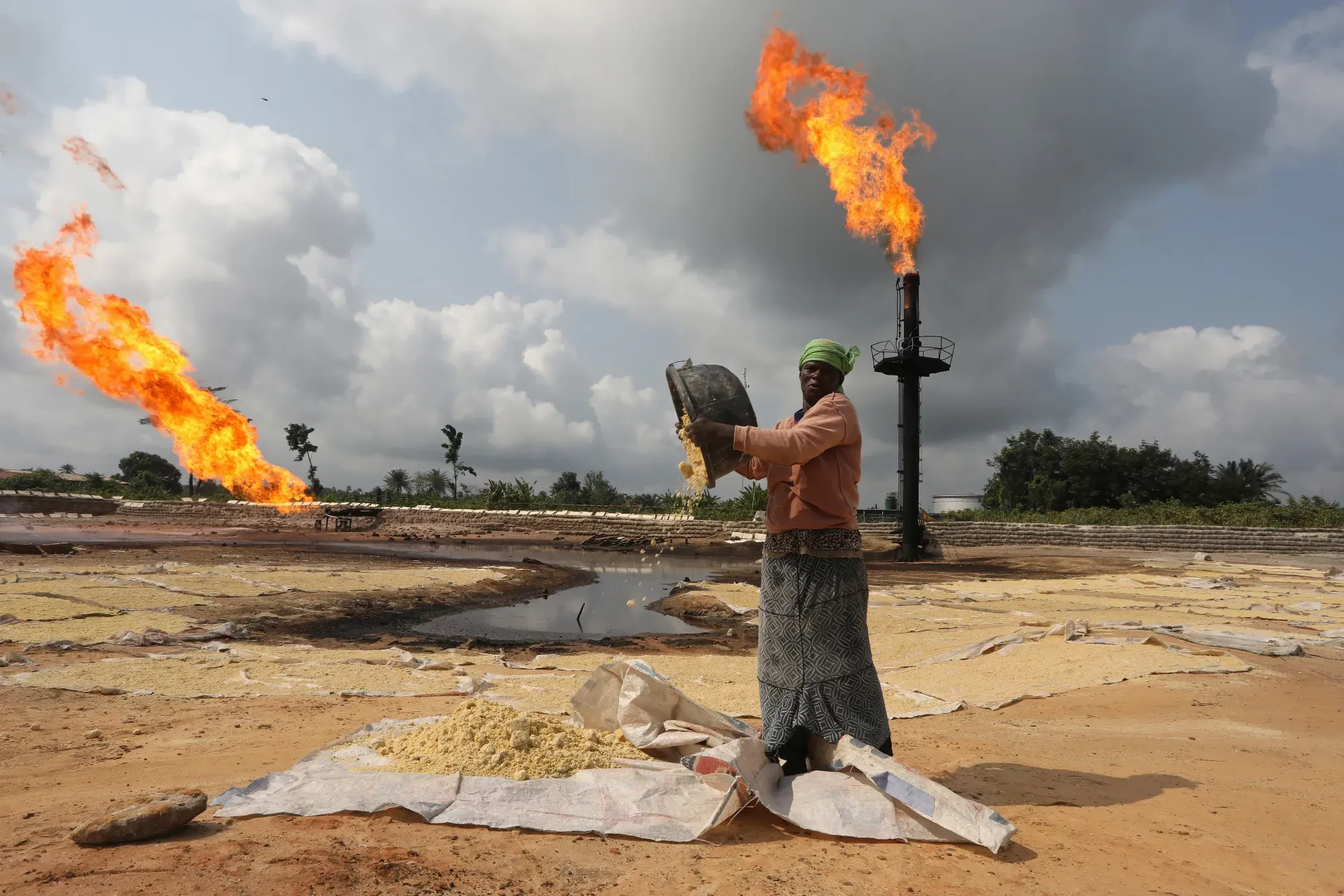African woman working with gas flares behind her